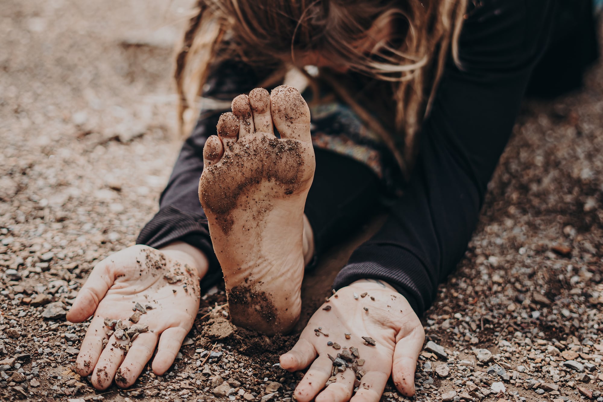 woman with outstretched arms and leg stretching on gravel covered ground
