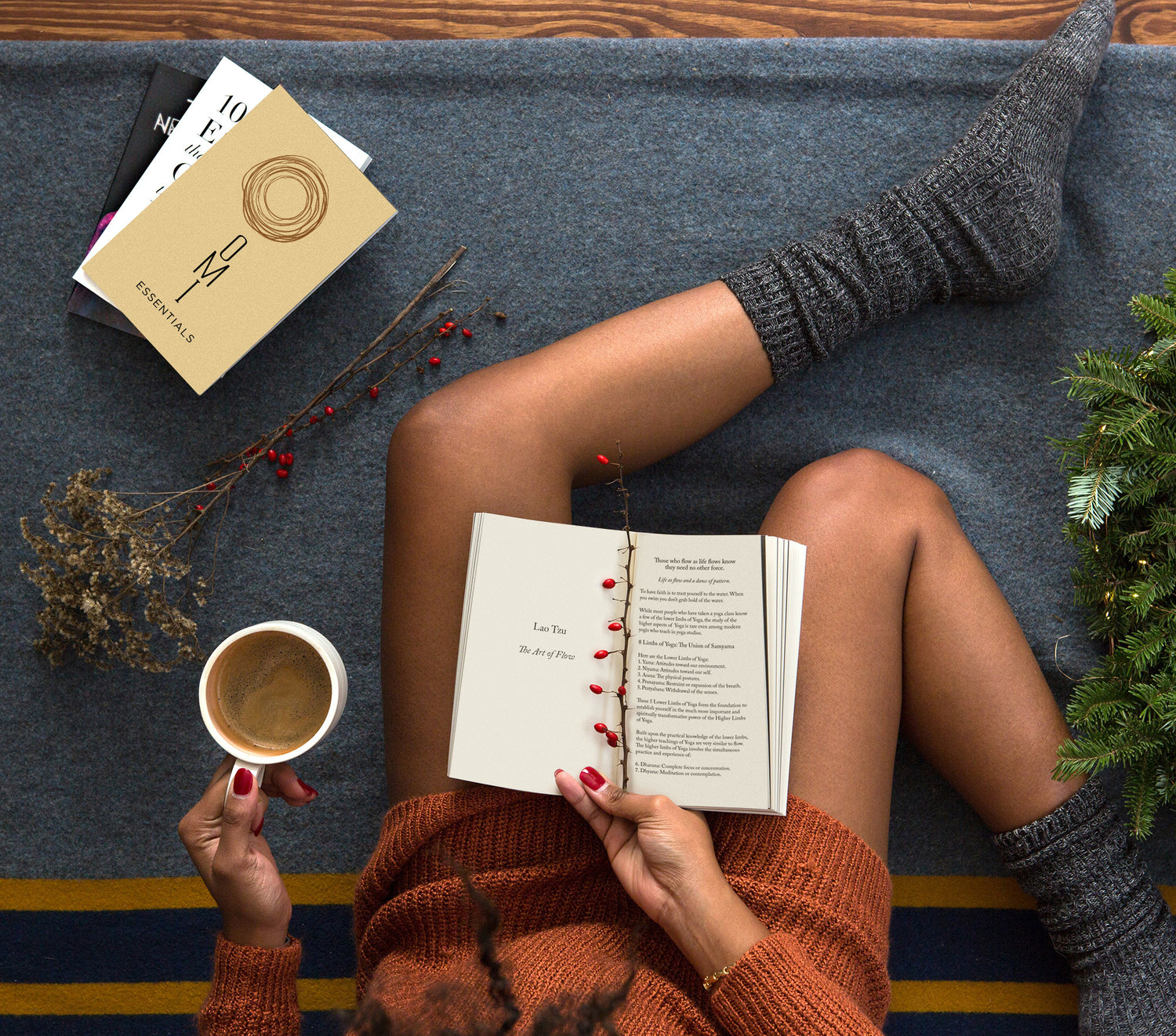 woman relaxing on blanket reading book and drinking coffee