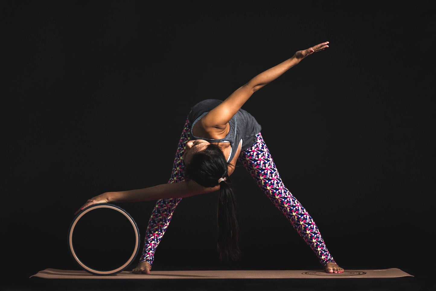woman stretching on yoga mat with OMI cork stretching wheel